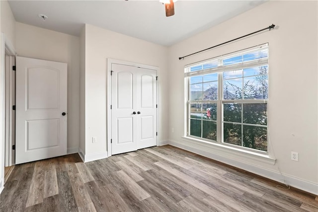 unfurnished bedroom with hardwood / wood-style floors, a closet, and ceiling fan