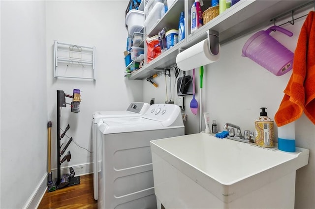 washroom with separate washer and dryer, sink, and dark wood-type flooring