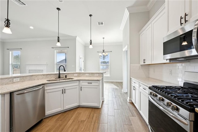 kitchen with pendant lighting, sink, white cabinetry, stainless steel appliances, and light stone countertops