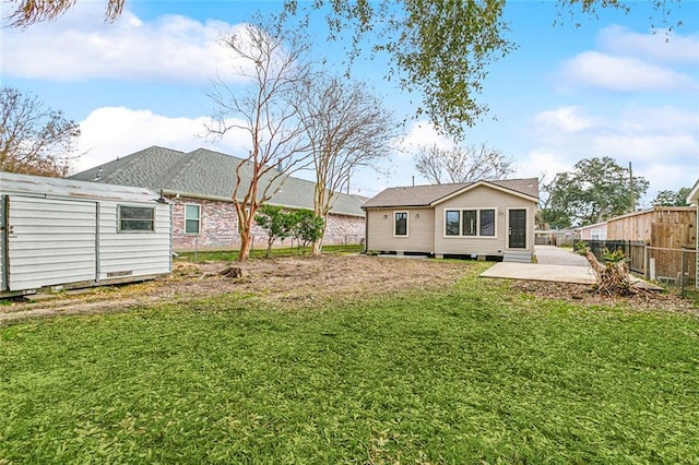 rear view of house with a patio, a lawn, and a storage shed