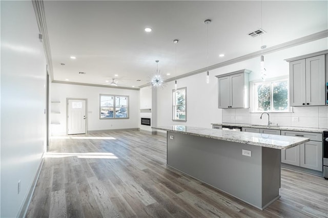 kitchen with hanging light fixtures, sink, a center island, and gray cabinetry