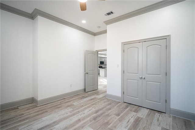 unfurnished bedroom with ornamental molding, a closet, ceiling fan, and light wood-type flooring