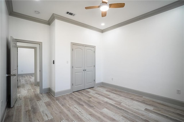 unfurnished bedroom with ceiling fan, ornamental molding, a closet, and light wood-type flooring