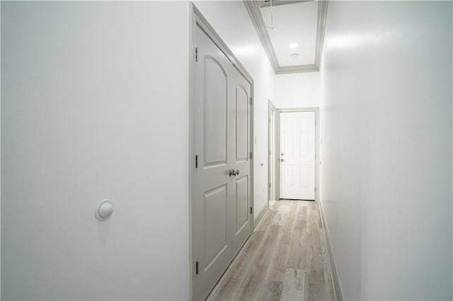 corridor with ornamental molding and light hardwood / wood-style floors