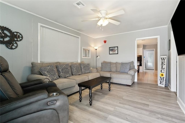 living room featuring ceiling fan, ornamental molding, and light wood-type flooring