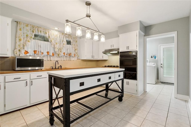 kitchen featuring sink, white cabinetry, pendant lighting, washer / clothes dryer, and backsplash