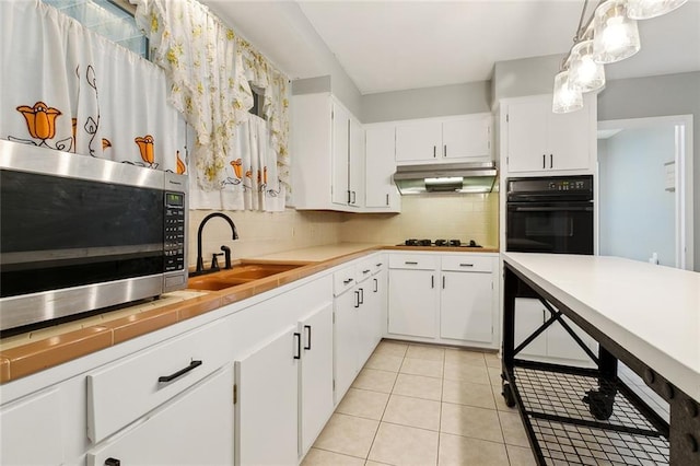 kitchen with sink, light tile patterned floors, white cabinetry, decorative light fixtures, and oven