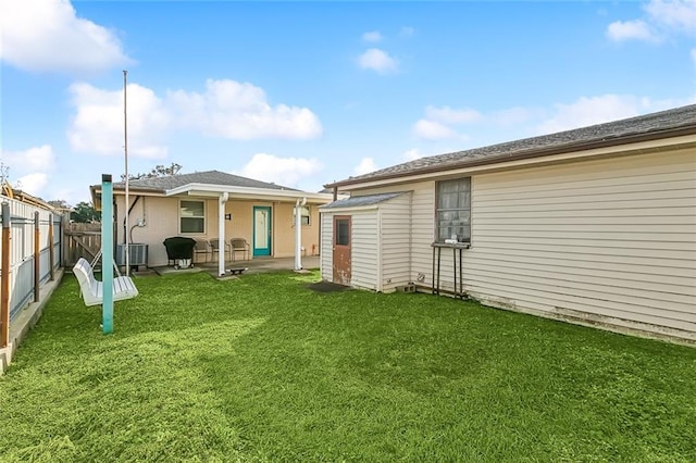 rear view of property featuring a storage shed, a yard, and central air condition unit