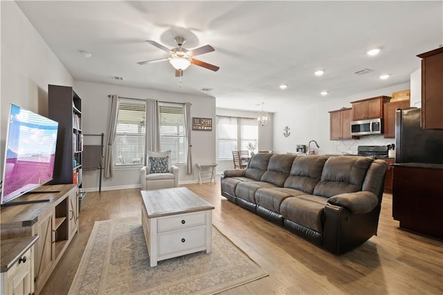 living room with ceiling fan with notable chandelier and light wood-type flooring