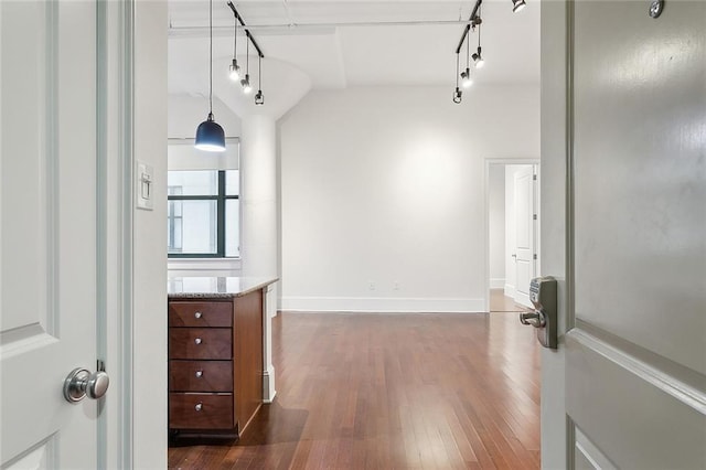 corridor featuring lofted ceiling, dark hardwood / wood-style floors, and rail lighting