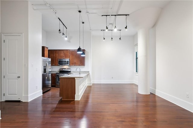 kitchen featuring dark hardwood / wood-style flooring, hanging light fixtures, a high ceiling, kitchen peninsula, and stainless steel appliances