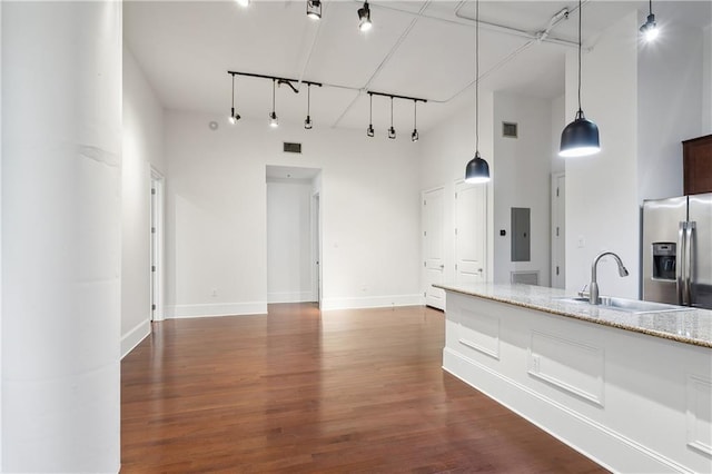 kitchen with sink, decorative light fixtures, stainless steel fridge, electric panel, and a high ceiling