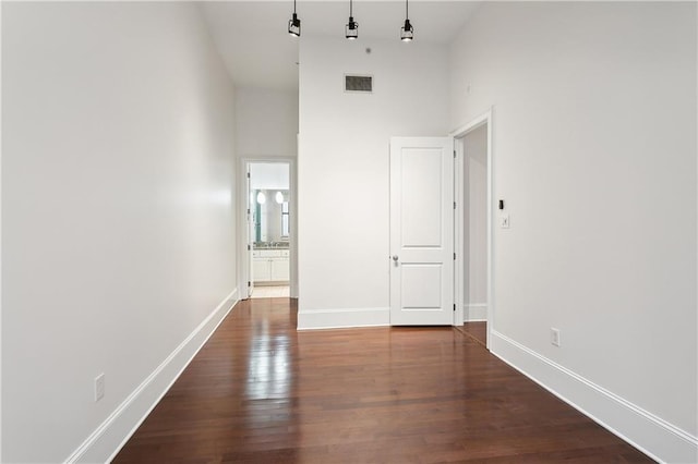 unfurnished room with dark wood-type flooring and a towering ceiling