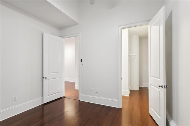 unfurnished bedroom with dark hardwood / wood-style flooring and a spacious closet