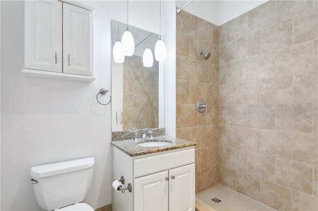 bathroom with vanity, toilet, and a tile shower