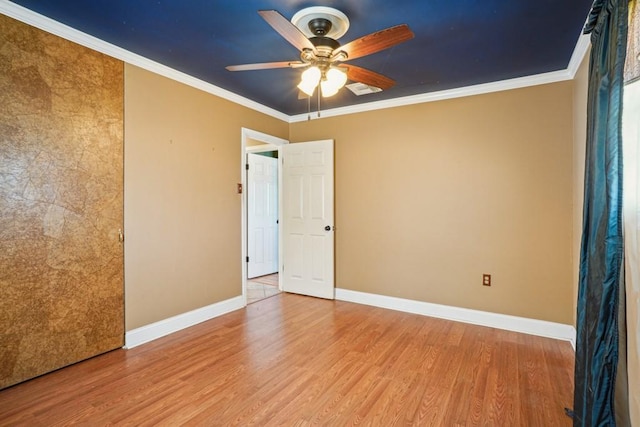 spare room with baseboards, ornamental molding, and wood finished floors