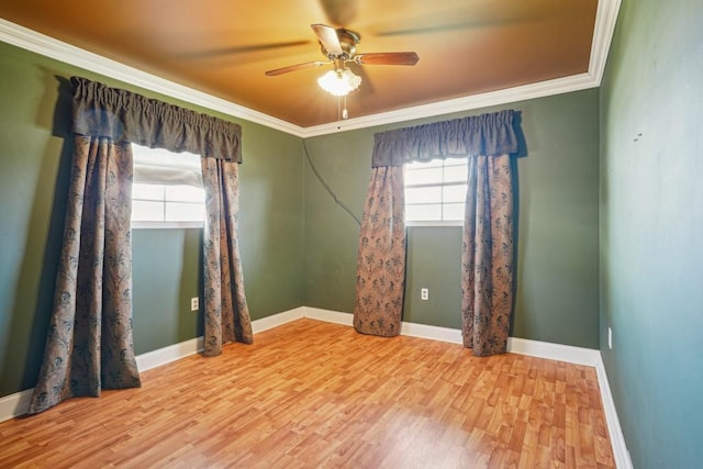 empty room with ceiling fan, crown molding, baseboards, and wood finished floors