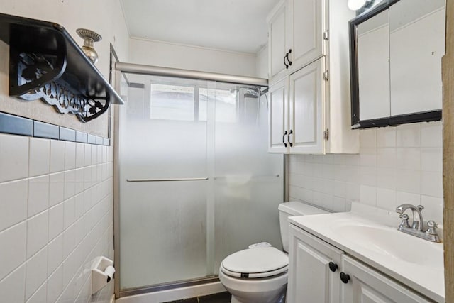 full bathroom with a stall shower, tile walls, toilet, and vanity