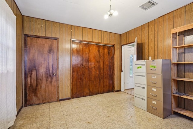 bedroom featuring light floors, visible vents, a closet, and wood walls