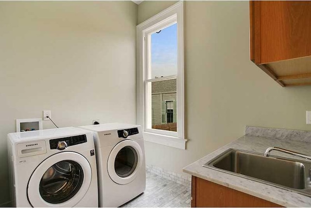 laundry area featuring sink, light hardwood / wood-style flooring, cabinets, and washer and dryer