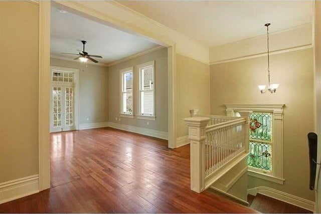 interior space featuring dark wood-type flooring, crown molding, and ceiling fan with notable chandelier