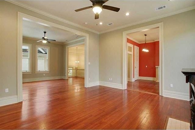 unfurnished living room with hardwood / wood-style floors, ornamental molding, and ceiling fan