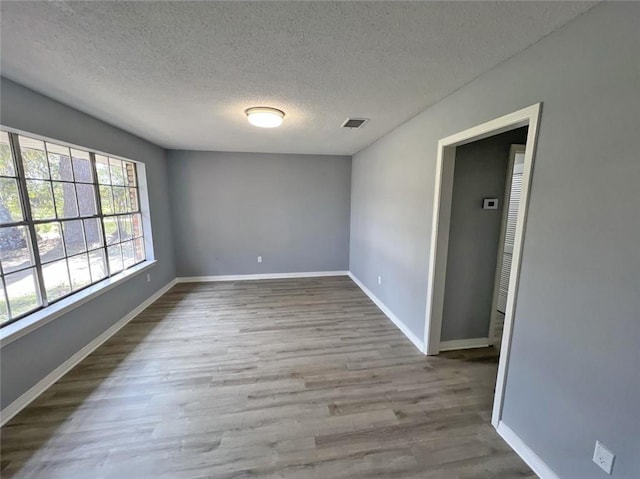 empty room with light hardwood / wood-style flooring and a textured ceiling