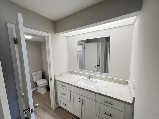 bathroom with wood-type flooring, vanity, and toilet