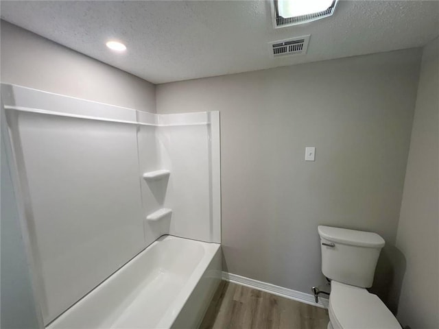 bathroom with a textured ceiling, toilet, hardwood / wood-style floors, and shower / bath combination