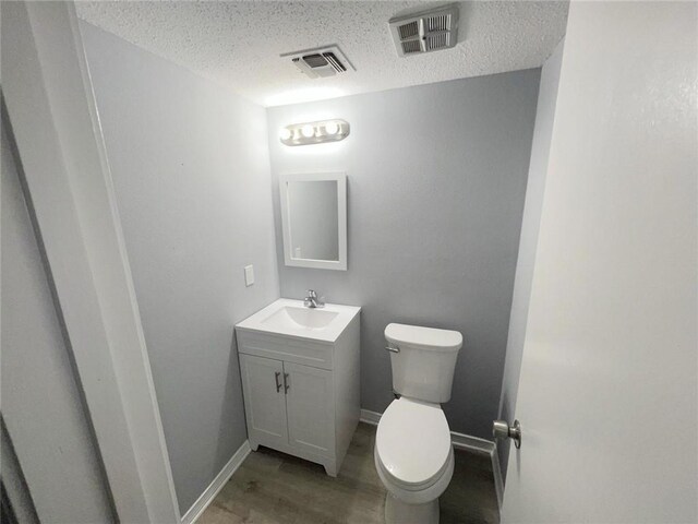 bathroom featuring vanity, wood-type flooring, a textured ceiling, and toilet