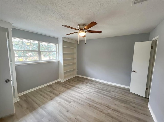 unfurnished room featuring light hardwood / wood-style flooring, ceiling fan, and a textured ceiling