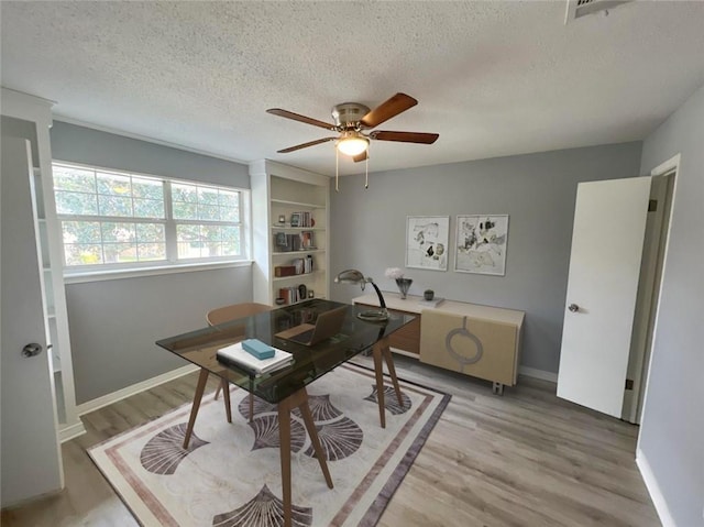 office space featuring ceiling fan, light wood-type flooring, and a textured ceiling