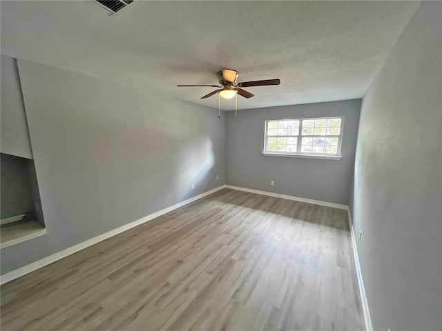 spare room featuring hardwood / wood-style flooring, ceiling fan, and a textured ceiling