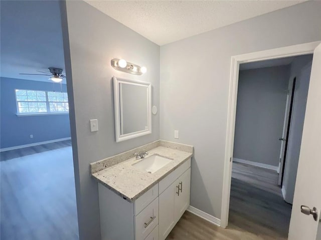 bathroom featuring vanity, hardwood / wood-style flooring, a textured ceiling, and ceiling fan