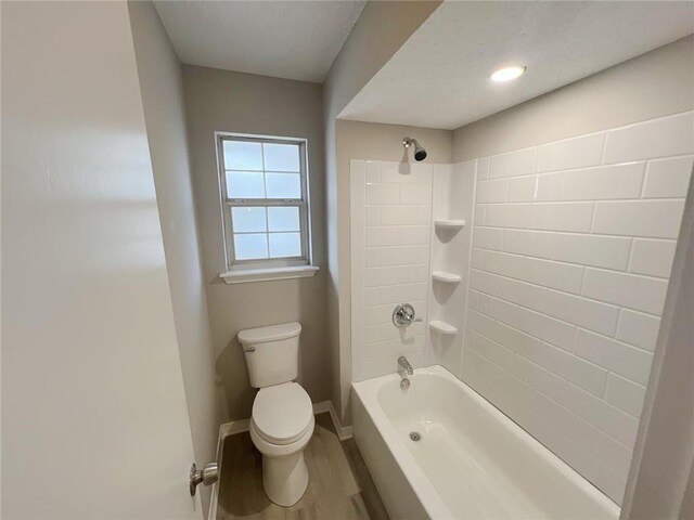 bathroom featuring tiled shower / bath, toilet, and hardwood / wood-style floors