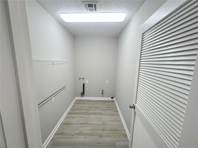 laundry room with light hardwood / wood-style flooring and a textured ceiling