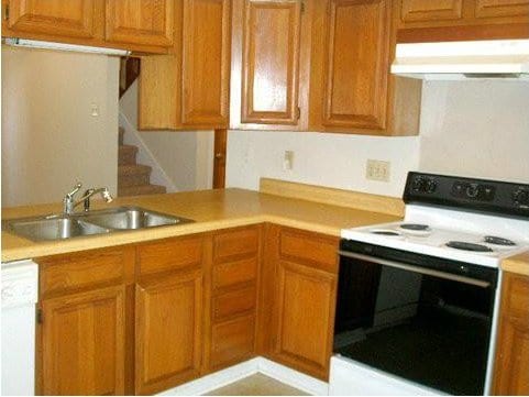 kitchen with electric range oven, sink, white dishwasher, and kitchen peninsula