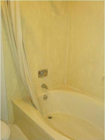 bathroom featuring shower / tub combo with curtain and toilet