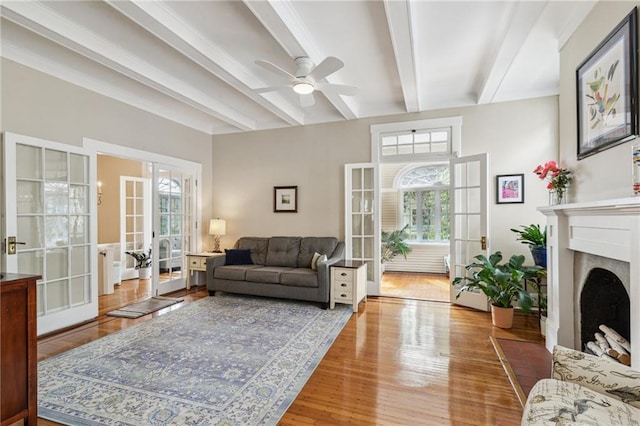 living room with beamed ceiling, hardwood / wood-style floors, ceiling fan, and french doors