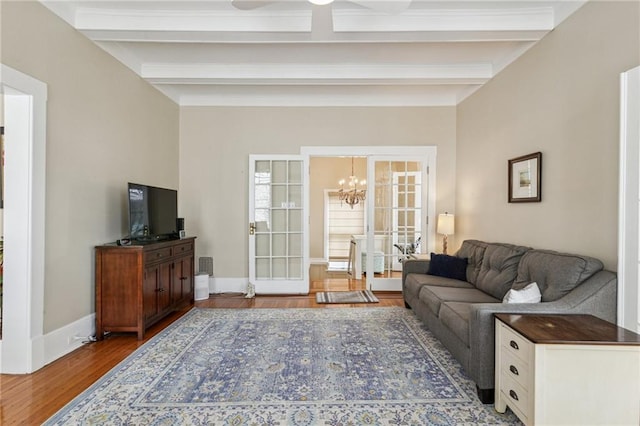 living room featuring hardwood / wood-style flooring, beam ceiling, an inviting chandelier, and french doors