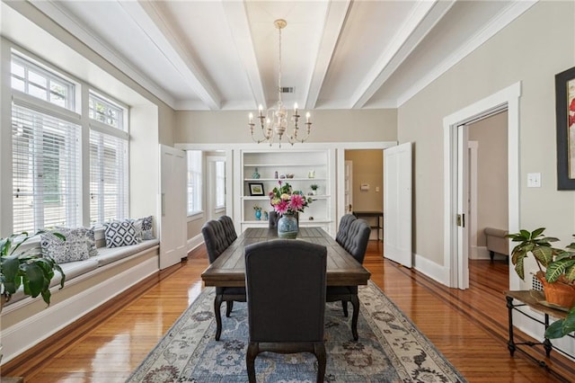 dining space with beamed ceiling, hardwood / wood-style flooring, an inviting chandelier, and built in shelves