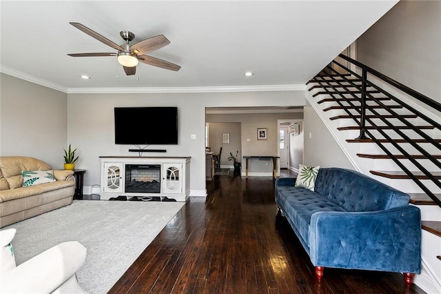 living room with a fireplace, dark wood-type flooring, ornamental molding, and ceiling fan