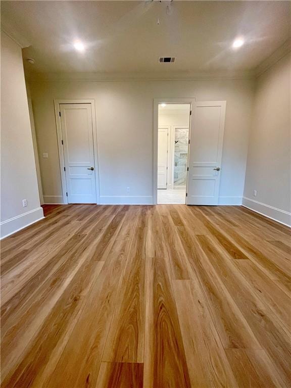 unfurnished bedroom with ornamental molding, ensuite bathroom, and light wood-type flooring