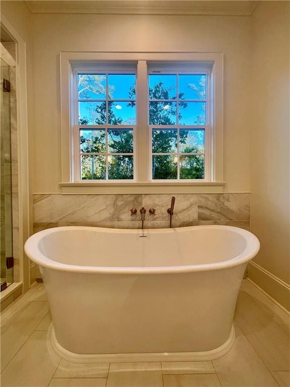 bathroom with tile patterned floors, separate shower and tub, tile walls, and a wealth of natural light