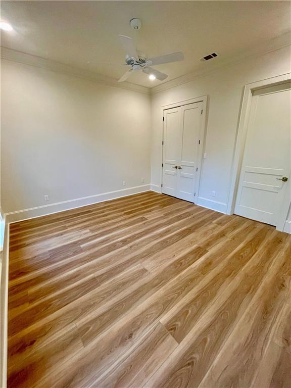 unfurnished bedroom featuring crown molding, ceiling fan, and light wood-type flooring