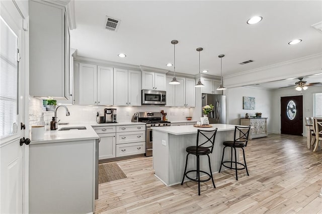 kitchen with sink, appliances with stainless steel finishes, hanging light fixtures, a center island, and decorative backsplash