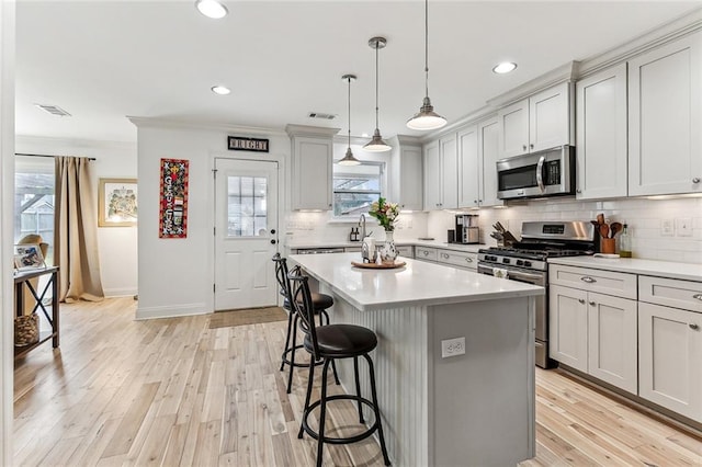 kitchen featuring tasteful backsplash, light hardwood / wood-style flooring, stainless steel appliances, and a center island