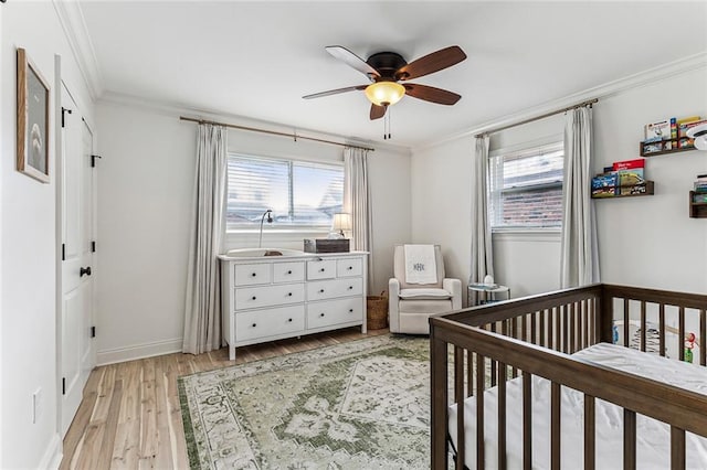 bedroom featuring crown molding, a nursery area, light hardwood / wood-style floors, and multiple windows