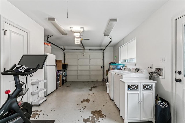 garage featuring washing machine and clothes dryer and white refrigerator