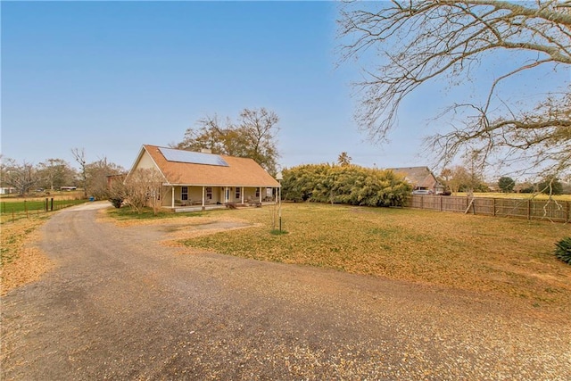 view of front of house featuring a porch, a front yard, and solar panels